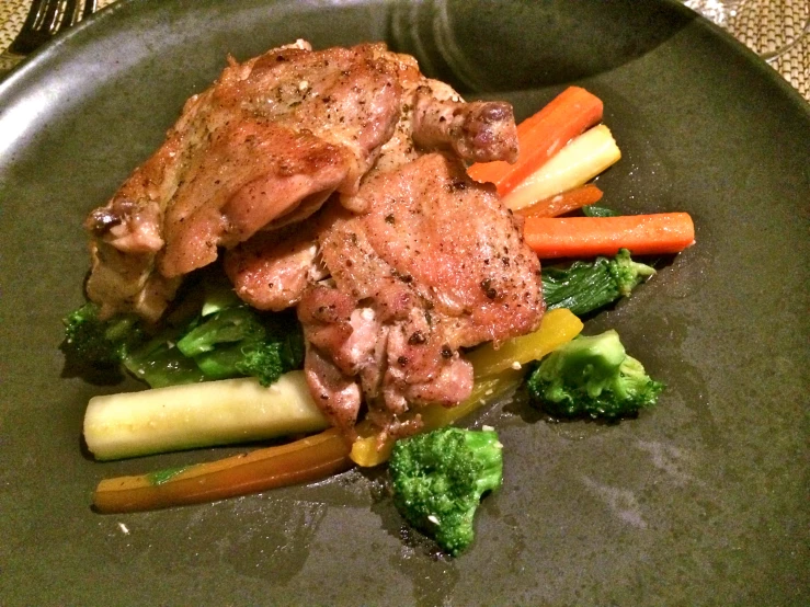 a large meal of meat, carrots and broccoli is on a gray plate