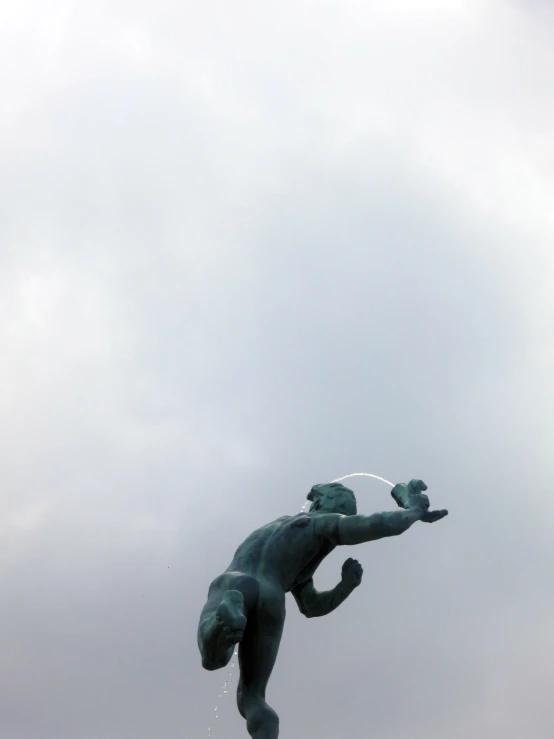 a statue holding an object in his hand on a cloudy day