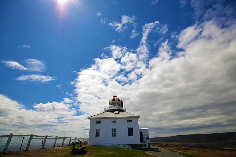 a white light house sitting on top of a hill