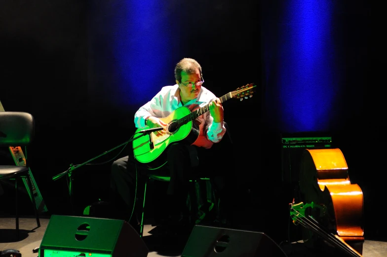 an older man is playing the guitar on stage