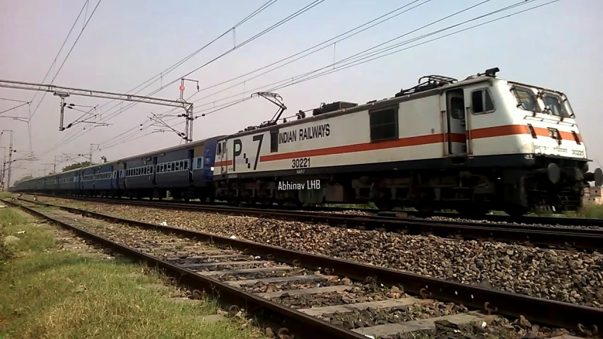 a passenger train is on the tracks with wires above it