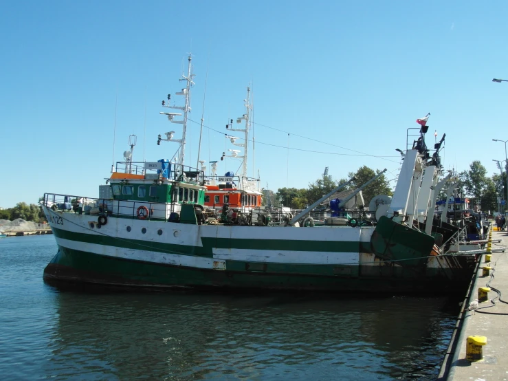 a green and white boat sitting in a body of water