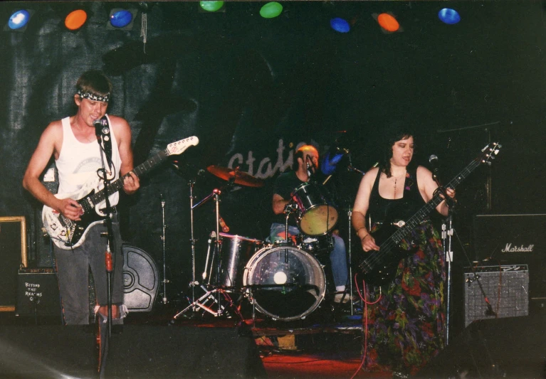 three people on stage with instruments and microphones