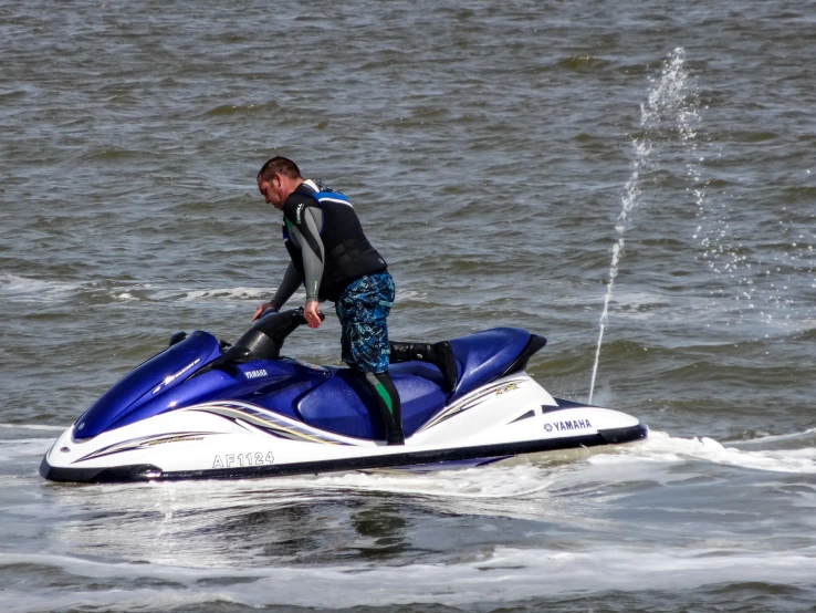 a man in black shirt riding a blue and white jet ski