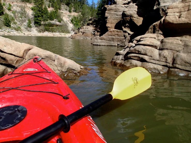 a kayak floating on a body of water with a rocky cliff in the background