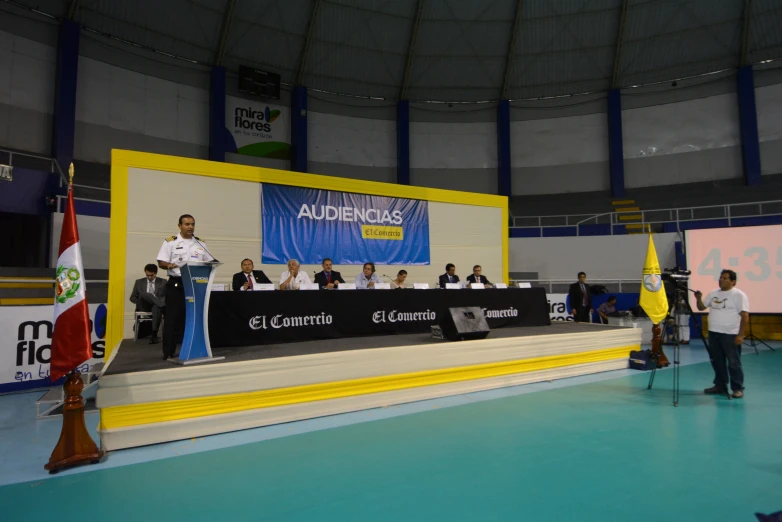 a man is speaking at a conference while people watch from the podiums