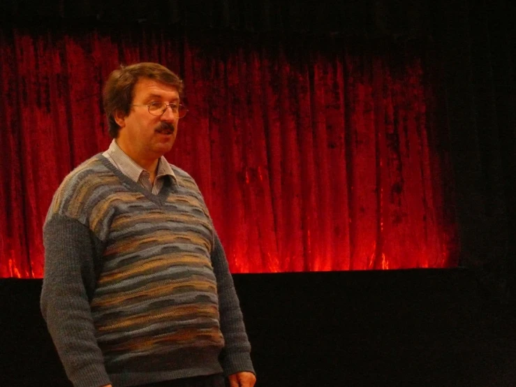 a man standing in front of a red curtain