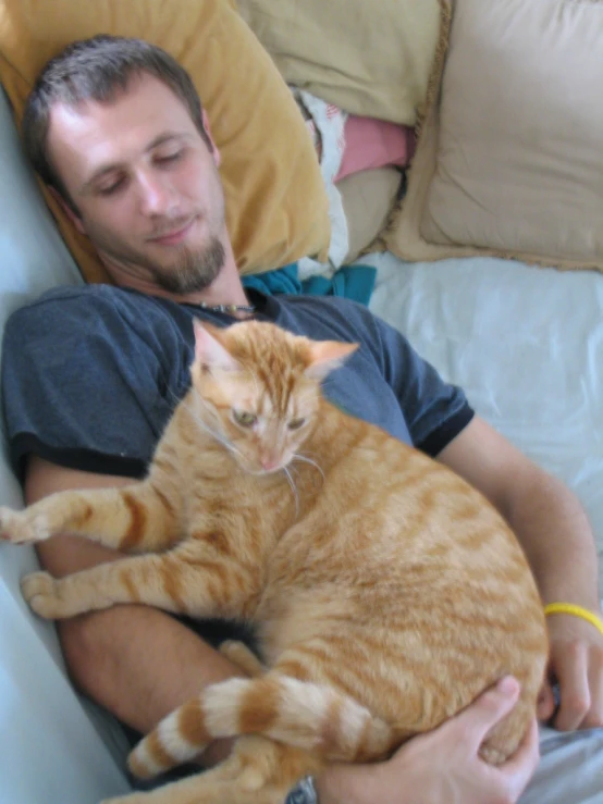 a man laying on a couch holding a cat