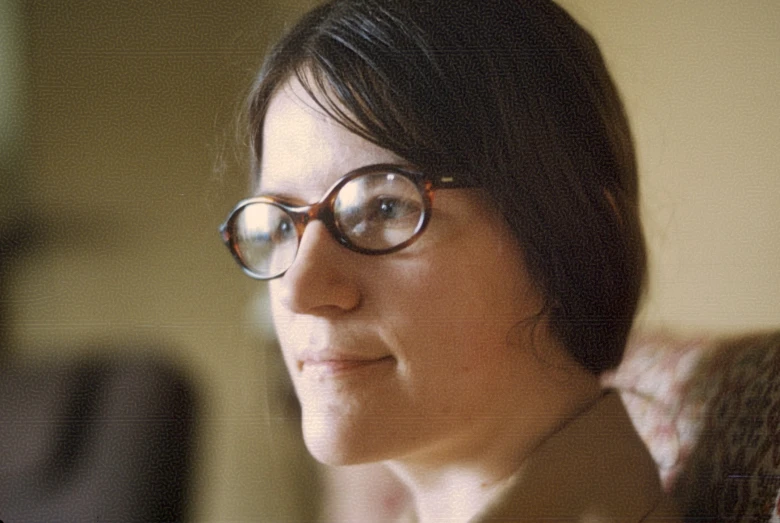 a woman wearing glasses sitting in an orange chair