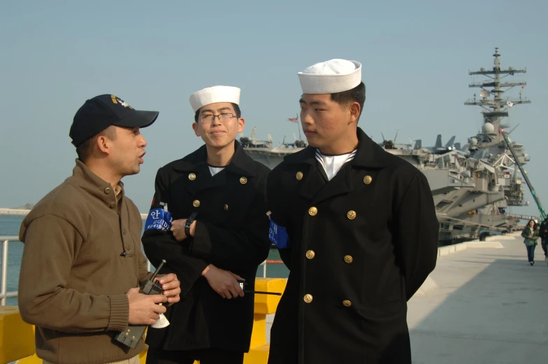 two navy men in uniform are talking to one another