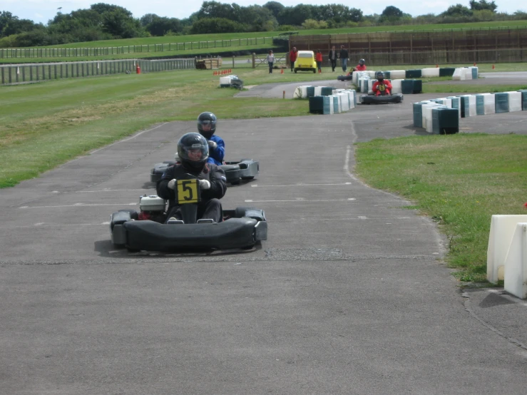 two people riding down a road on three go - karts