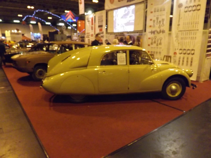 yellow car sitting on a red carpet in a museum