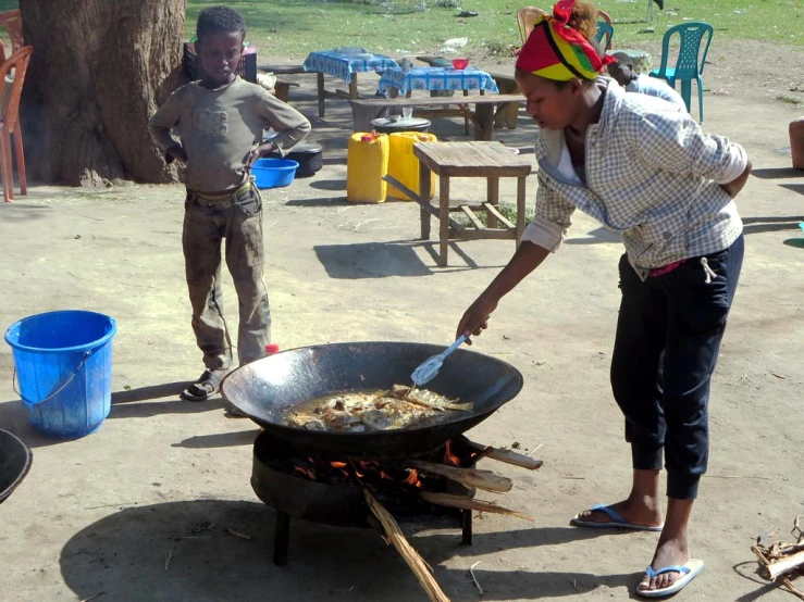 the woman is stirring food on the grill in the field