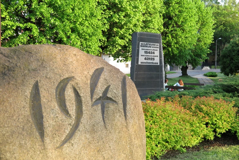 a rock with some writing on it with trees in the background