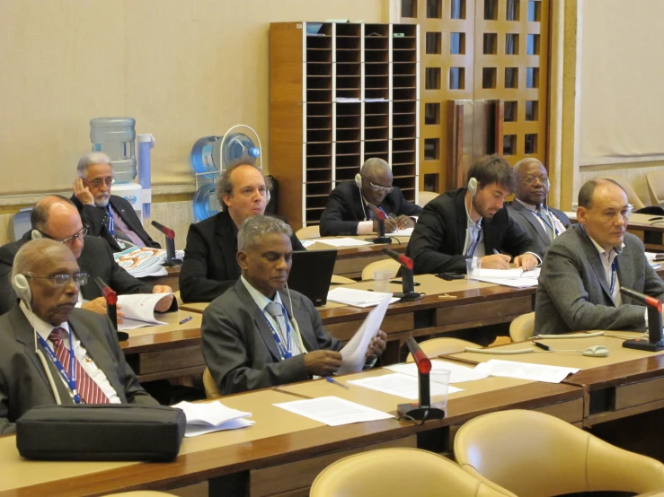 many men in suits and ties are sitting at desks