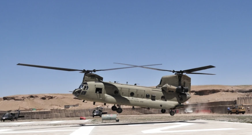 a large army helicopter with several people sitting on the back of it