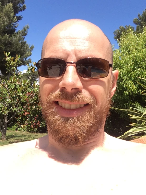 a man with shades standing near some trees