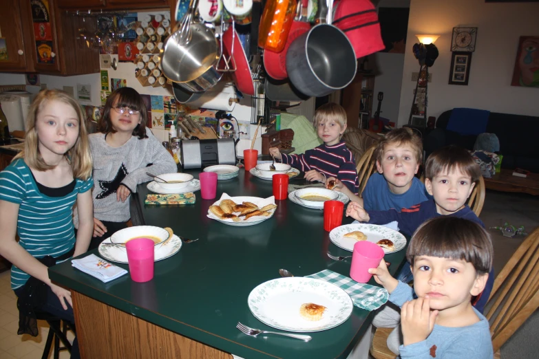 children sitting around a table with plates of food