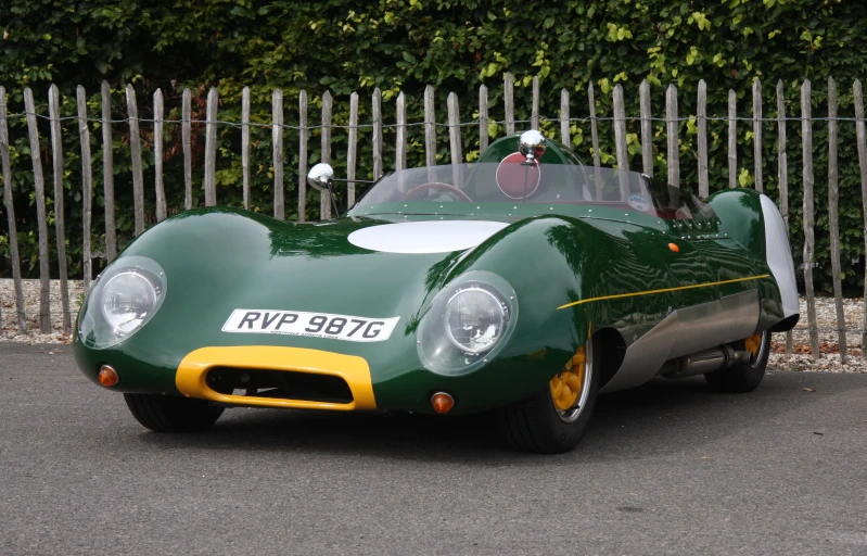 a green sports car sits parked by the fence