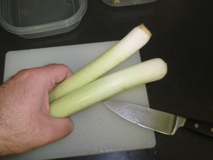 a person  celery on a  board with a knife