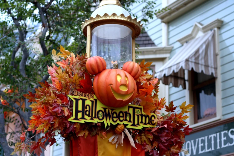 an orange lamp post with fake pumpkins and leaves