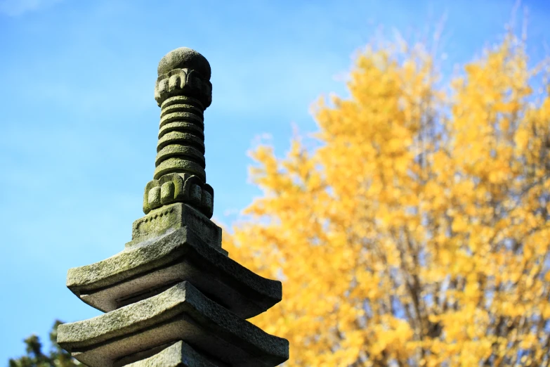 a sculpture that is near a tree and a sky background