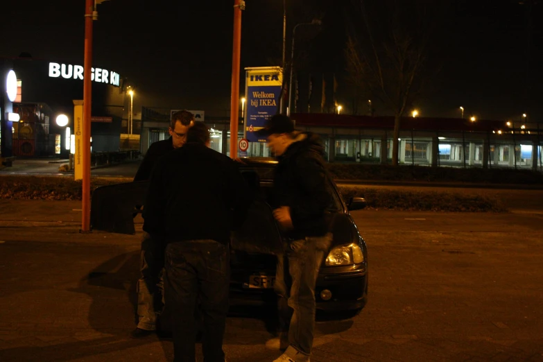 two men standing by their car at night