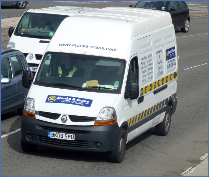 a white van driving down a street in front of other cars