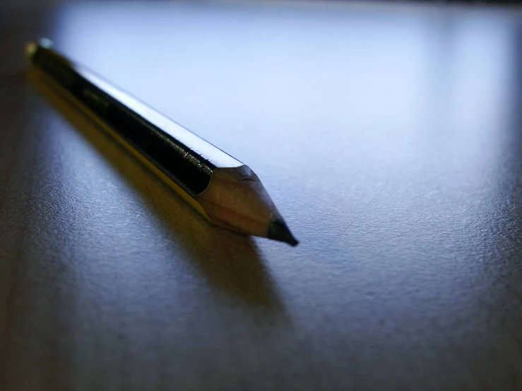an angled pen rests atop a wooden table