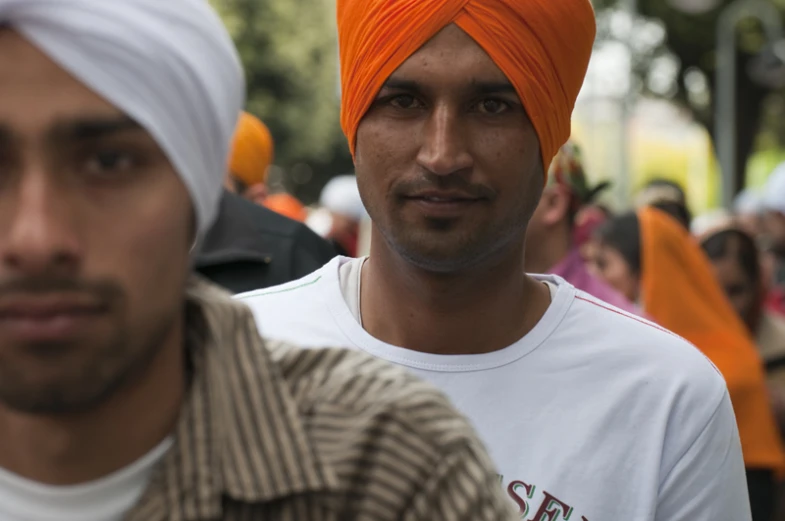 the men are standing near one another wearing turbans