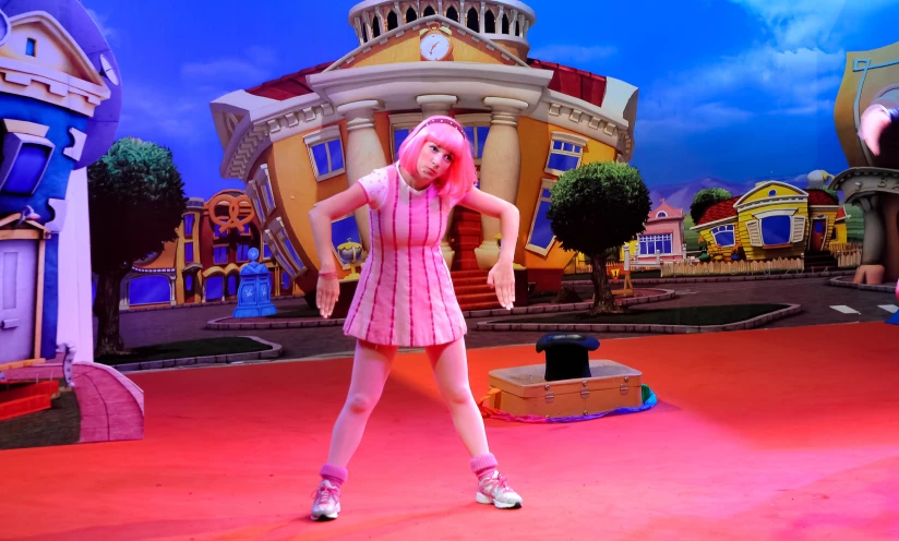 a person on a pink floor in front of a stage with buildings and blue sky