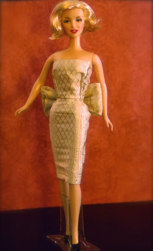 a barbie doll wearing a gold dress and black shoes