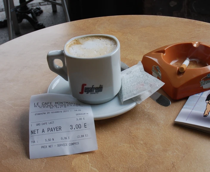 a coffee mug sits on top of a paper near a paper cutter