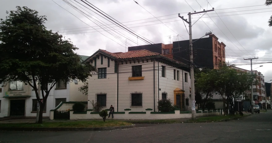 an old house with black windows sits on the corner of a street