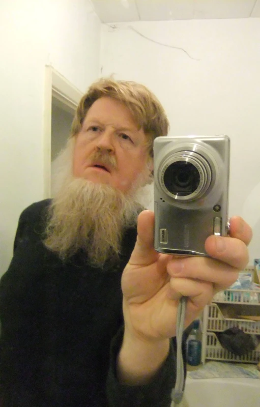 an older man holding a camera in a bathroom