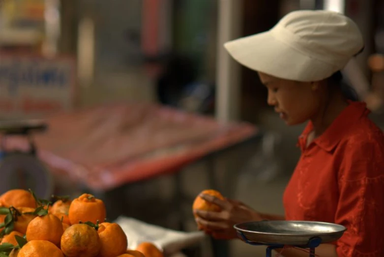 a woman in red shirt holding a bowl of oranges