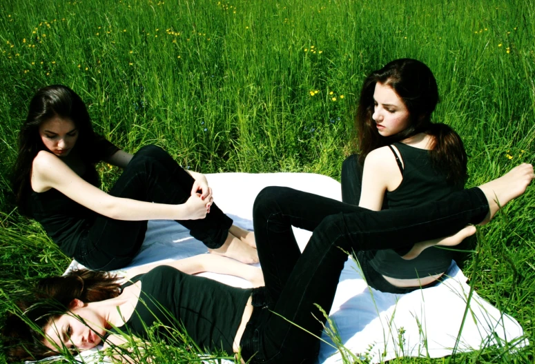 three women sitting in the grass posing for a po