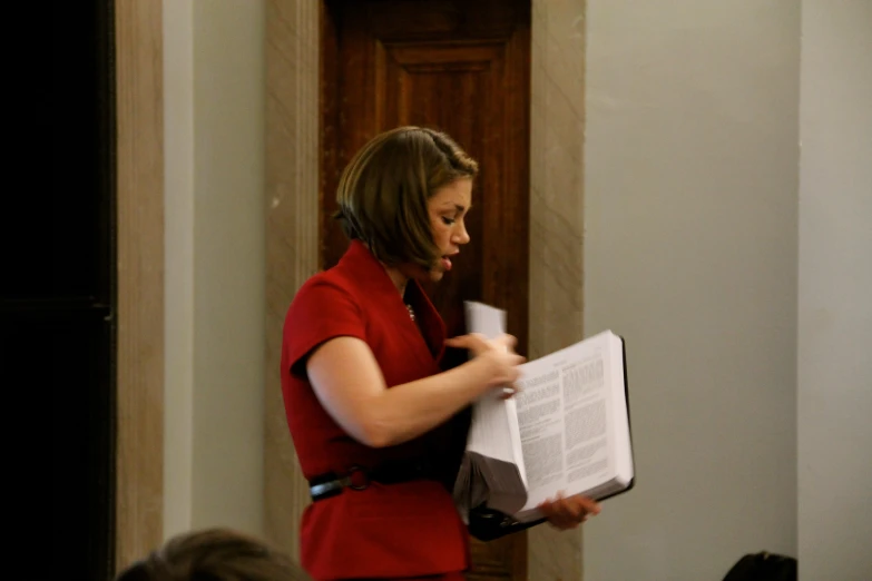 a woman wearing a red jacket holding a white piece of paper