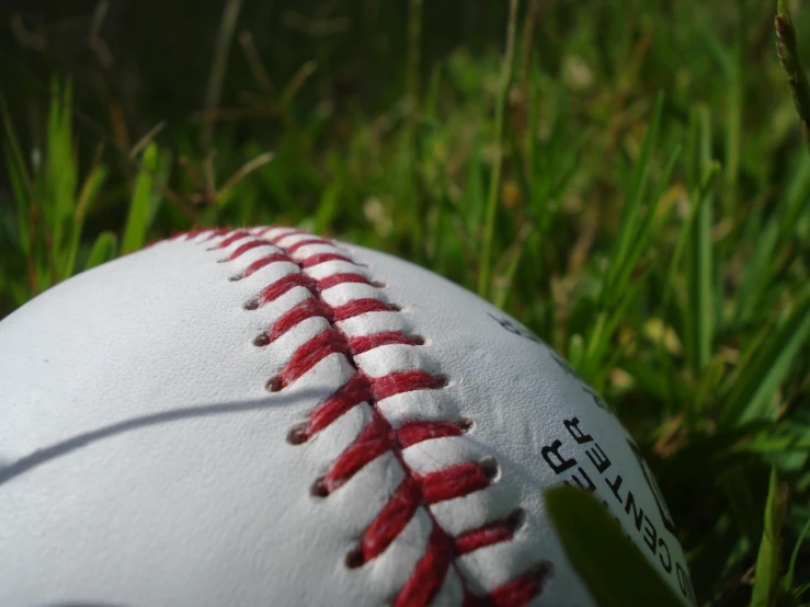 a white ball with red stitchs is in the grass