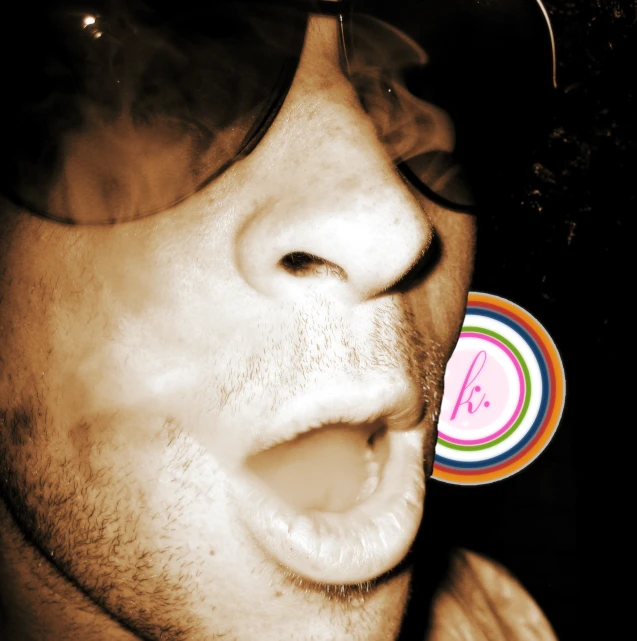 a man with sunglasses that is blowing out some smoke