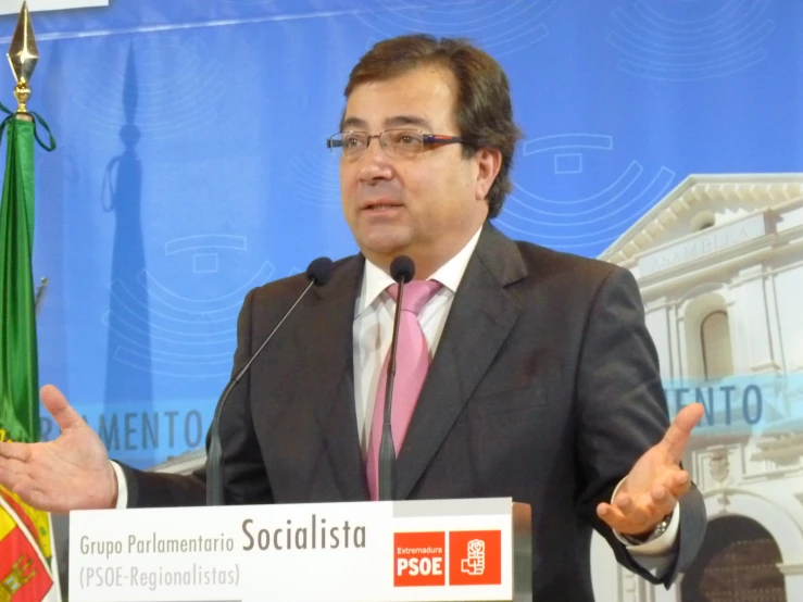 a man speaking into a microphone with a sign that reads people are socialistas