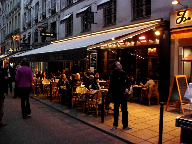 people are walking down the street in a large area with many tables