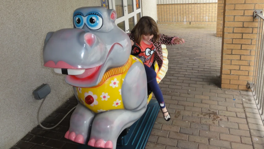 a girl riding on a toy elephant in an amut park