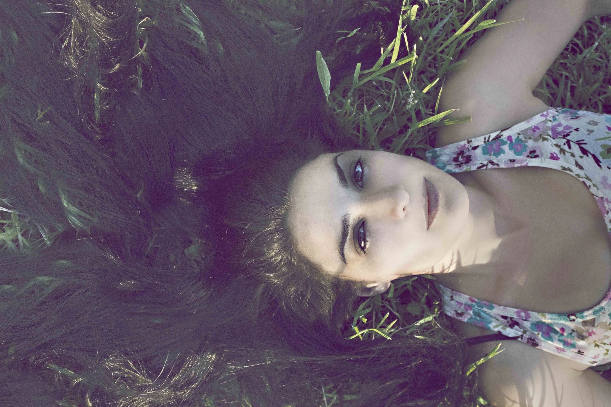 a girl in floral shirt laying on grass