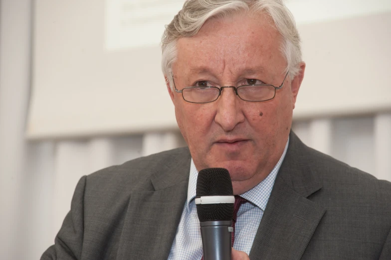 a man in suit and tie holding a microphone