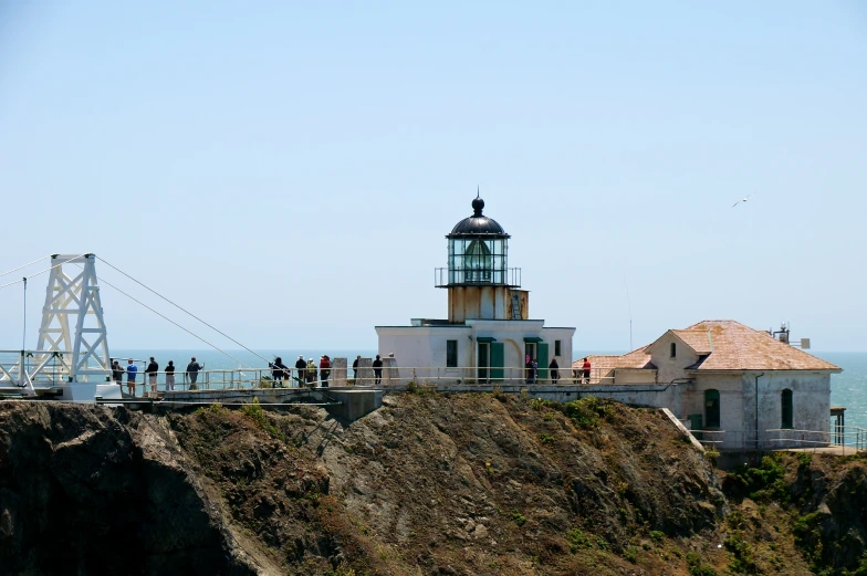 a lighthouse sitting on top of a cliff with people on it