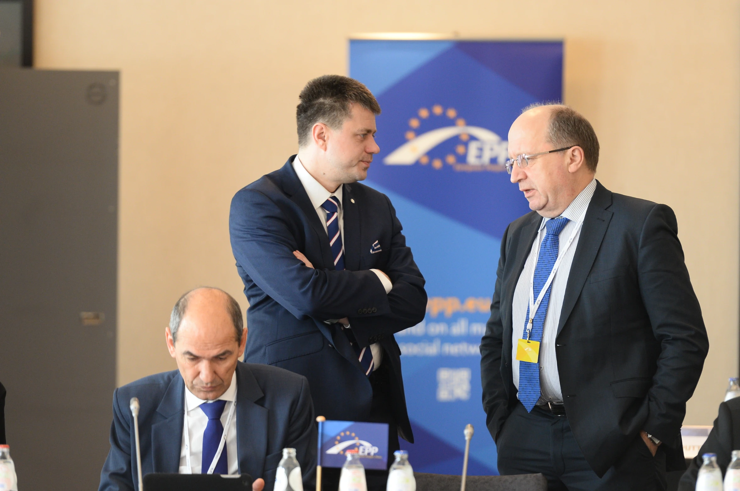 three men wearing suits in a meeting room