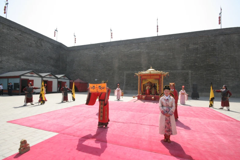 a group of people in chinese costumes standing on a pink and red carpet