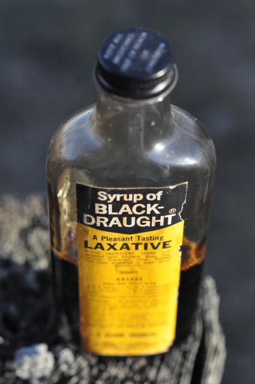 a bottle of liquid sitting on top of a piece of wood