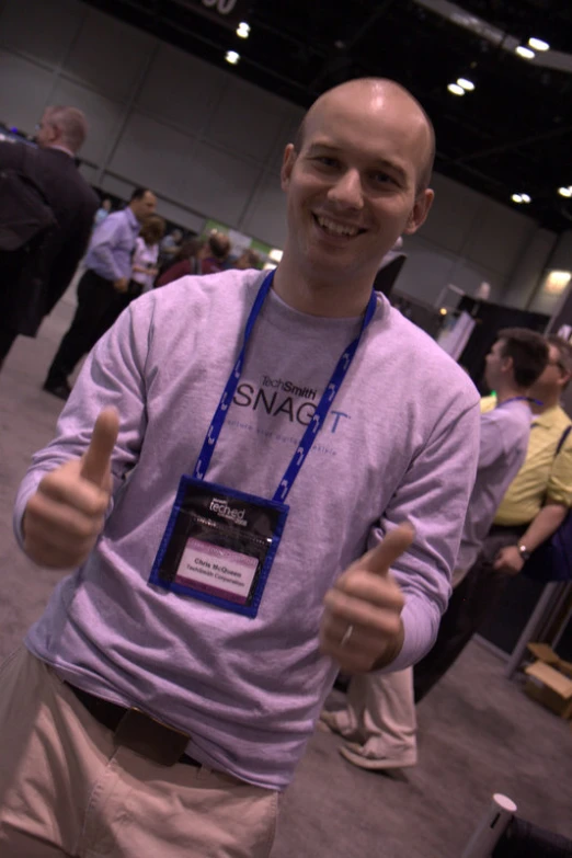 a smiling man giving a thumbs up in a room with people on the floor